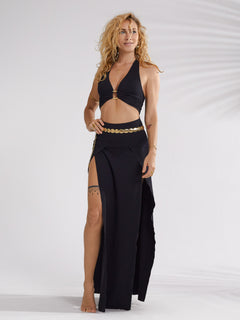 A model wearing a high-waisted, maxi-length black skirt with double slits, made from a soft fabric blend, in a studio setting.